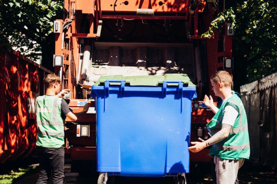 two stewards emptying a blue bin.